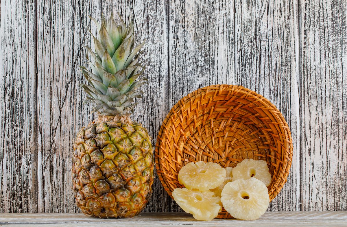 Whole pineapple next to a basket of dried pineapple rings