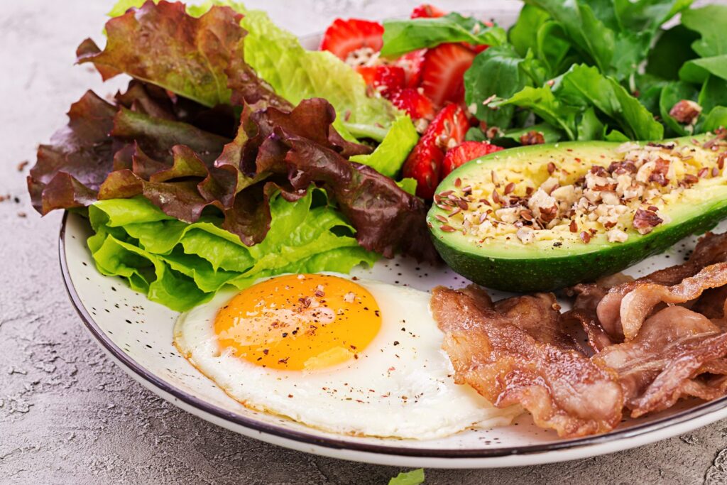 Ketogenic plate with fried egg, bacon, avocado and rocket