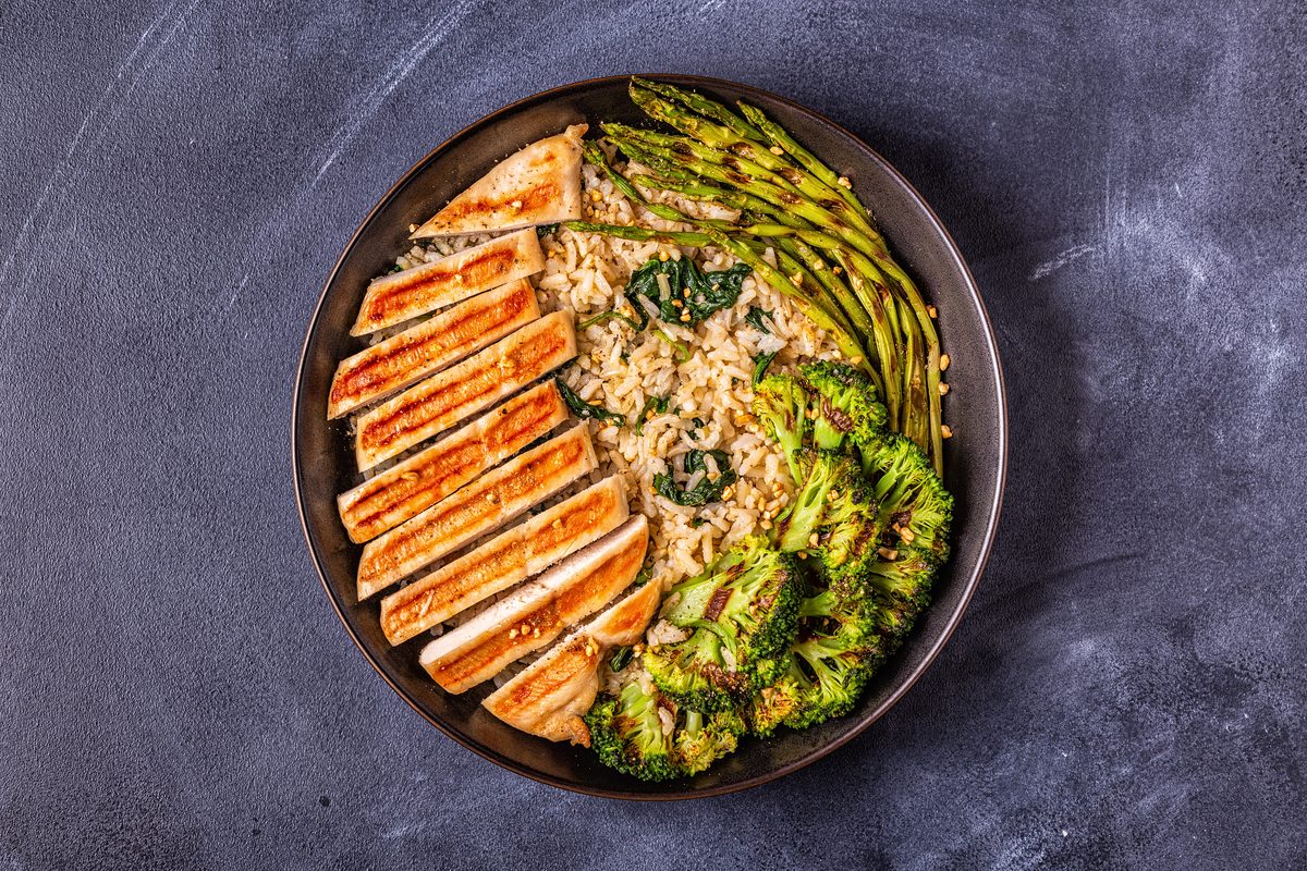 Plate of grilled chicken breast, brown rice, broccoli and asparagus