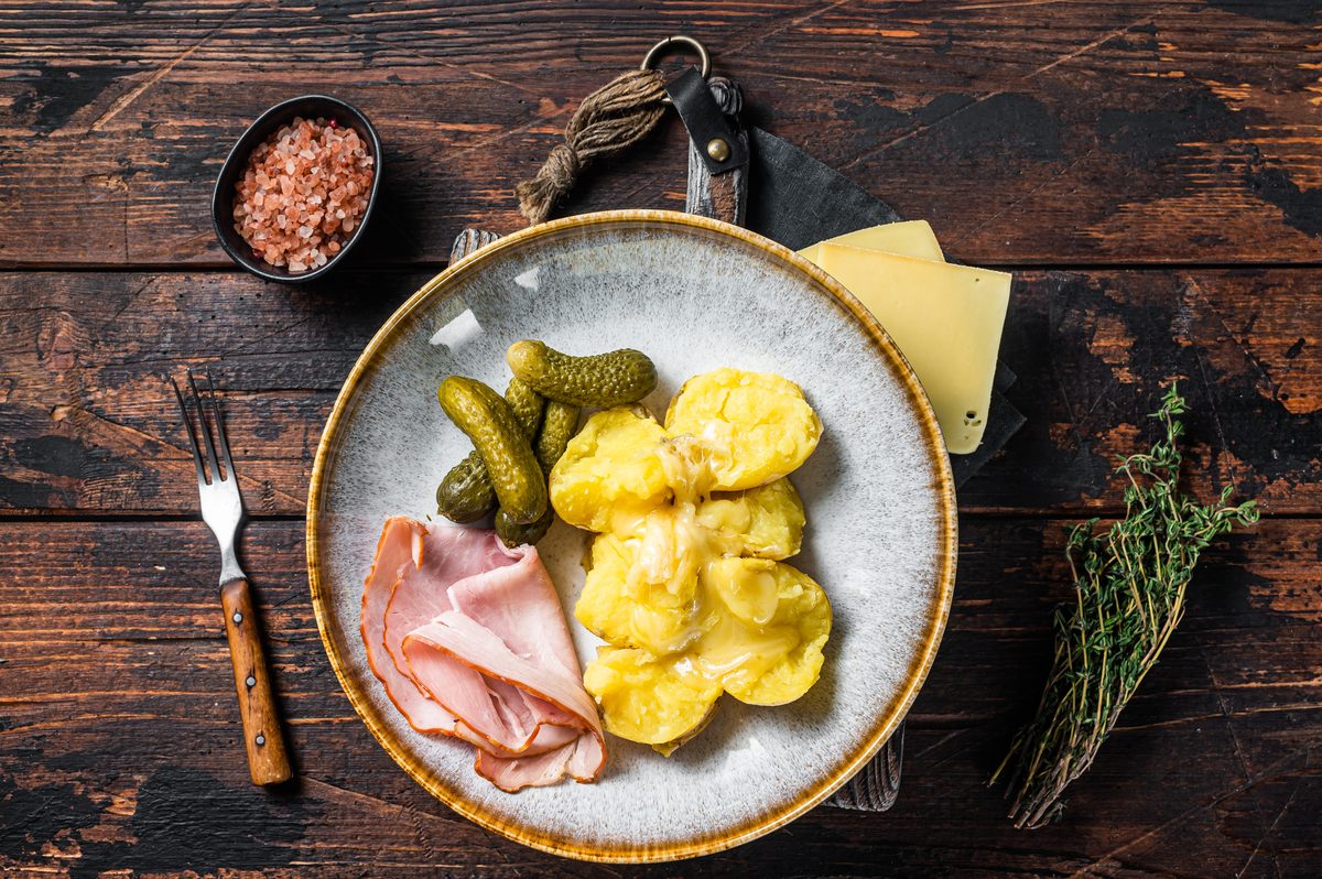 Plate of raclette with soft potatoes, ham and gherkins