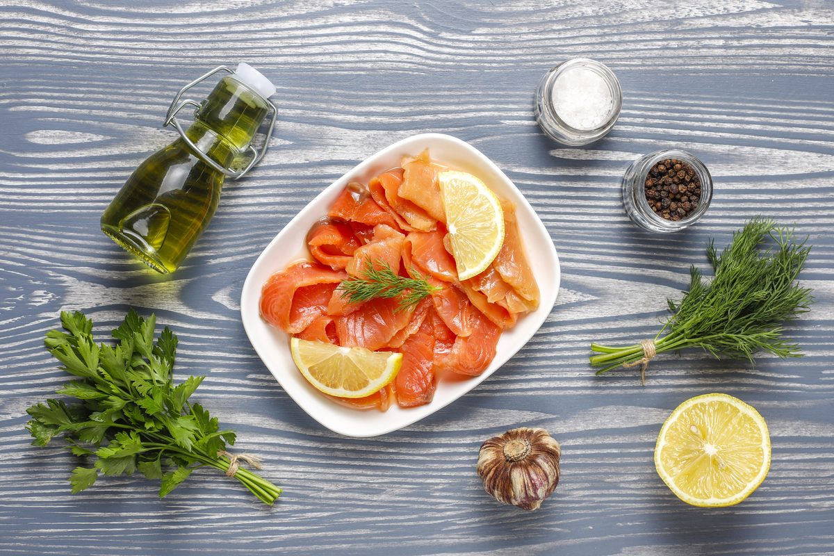 Plate of smoked salmon slices with lemon, dill and olive oil
