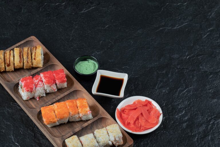 Assortment of sushi on a wooden board with wasabi, ginger and soy sauce