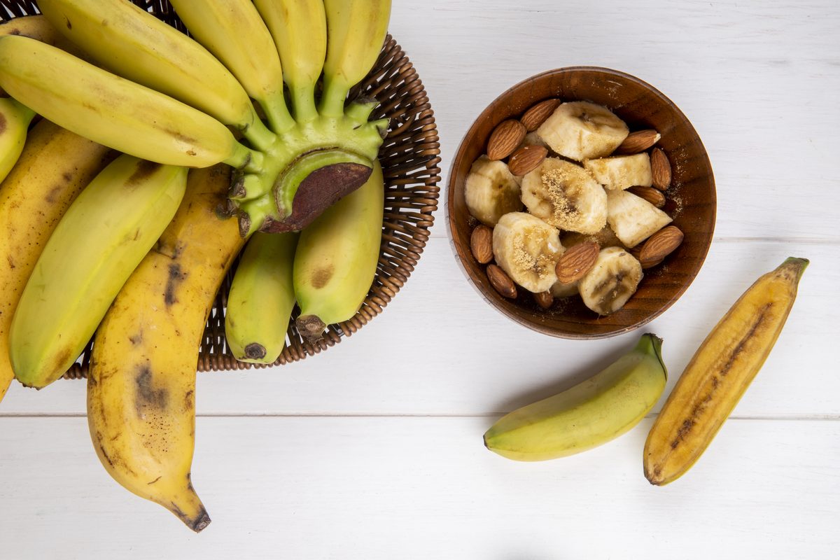 Bananas in a basket and a bowl of banana slices with almonds