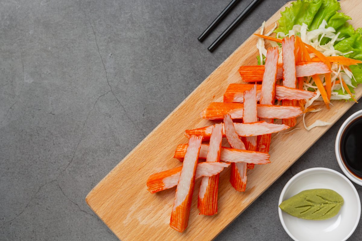 Shredded surimi sticks on a board with wasabi and soy sauce