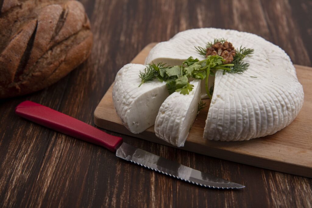 Block of feta on a board with a knife and bread