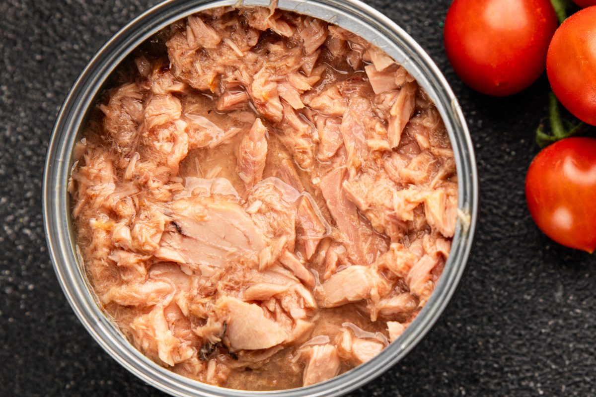 Open tin of tuna next to cherry tomatoes, seen from above
