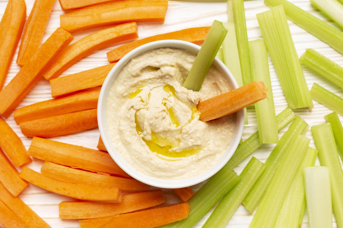 Bol de houmous entouré de bâtonnets de carottes et de céleri