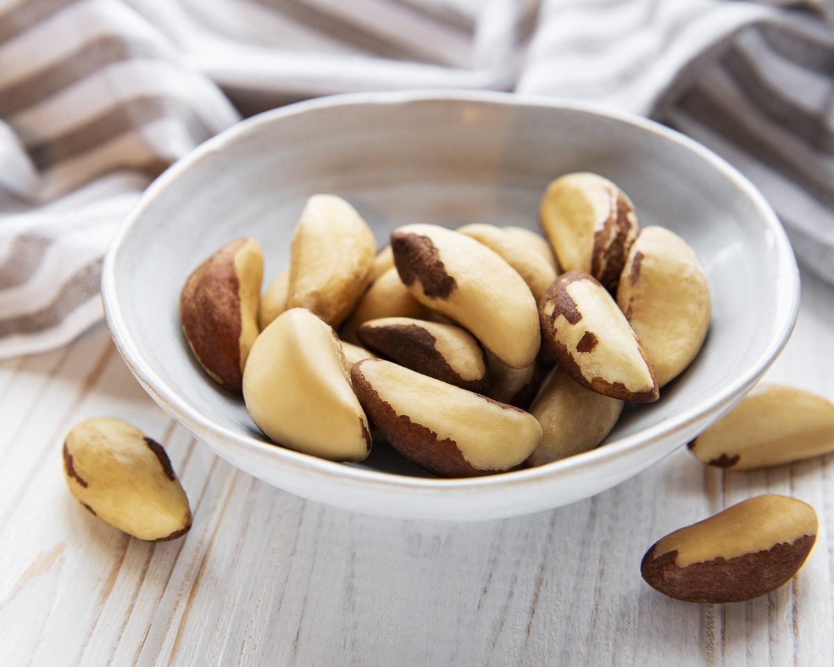 Bowl of Brazil nuts on a white wooden table