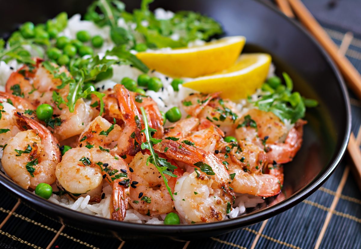Bowl of rice with cooked prawns, peas and rocket
