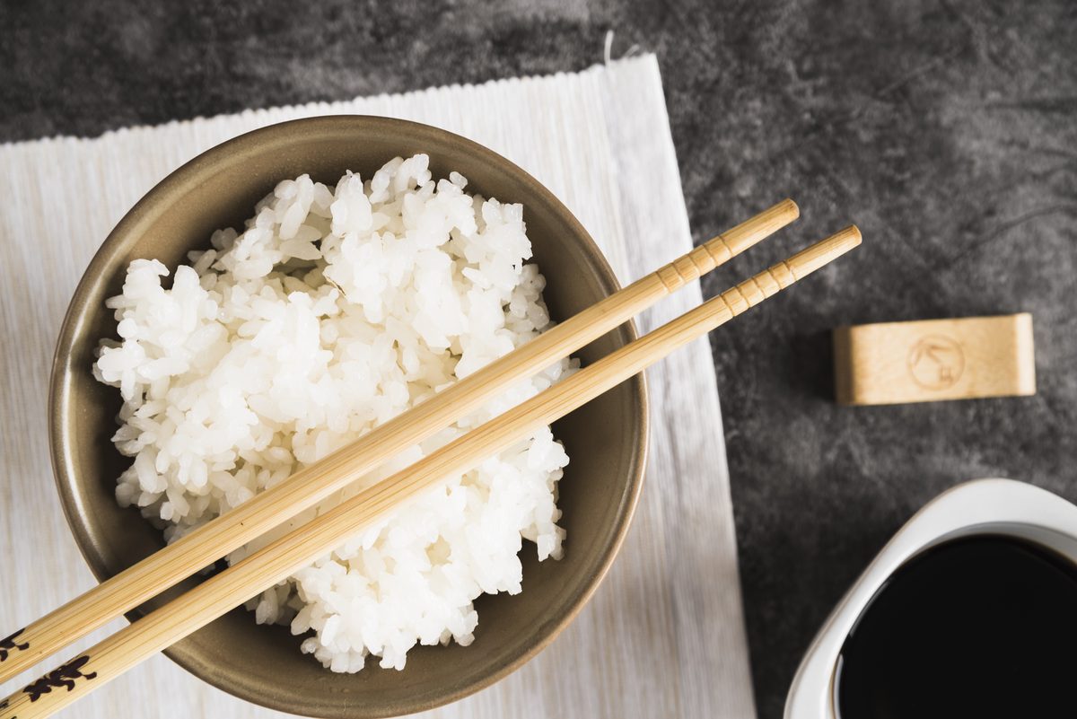 Bowl of cooked white rice with chopsticks and soy sauce