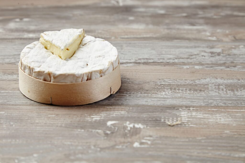 Cut Camembert in its wooden box on a table
