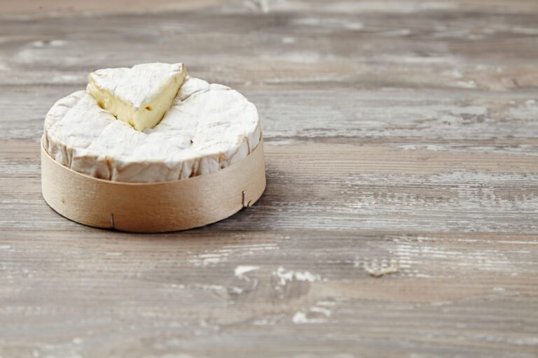 Cut Camembert in its wooden box on a table