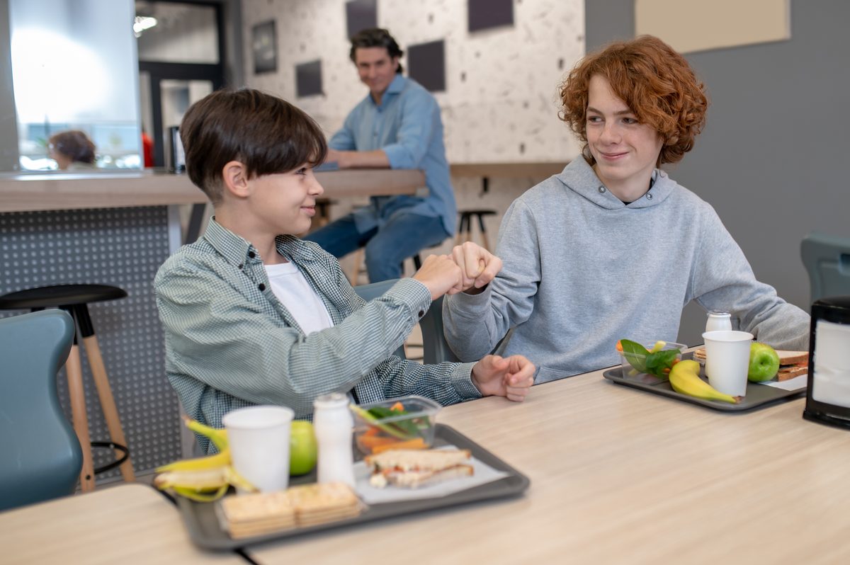 Schoolchildren having lunch in the canteen with a tray of fruit and sandwiches
