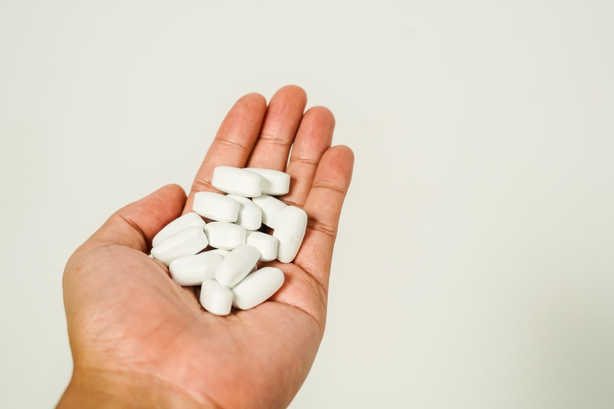 White calcium tablets in the palm of a hand