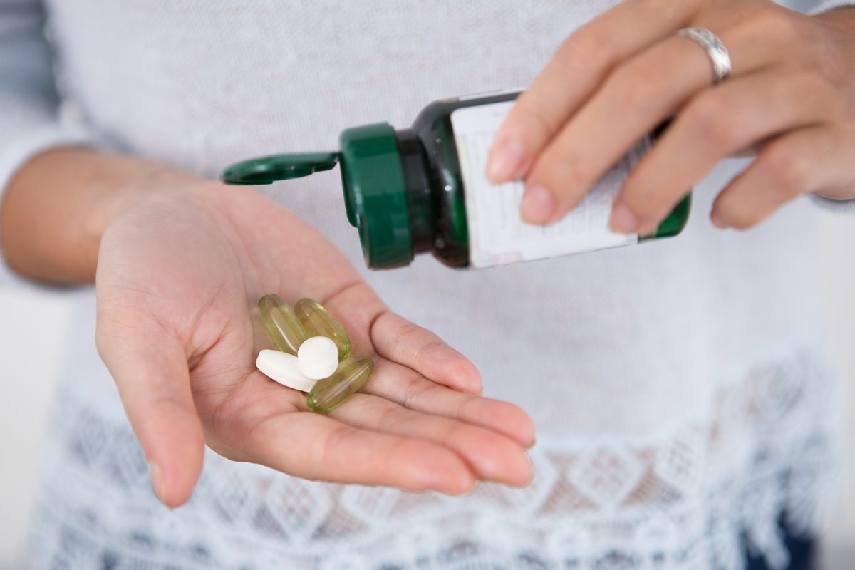 Supplement tablets poured from a bottle into a hand