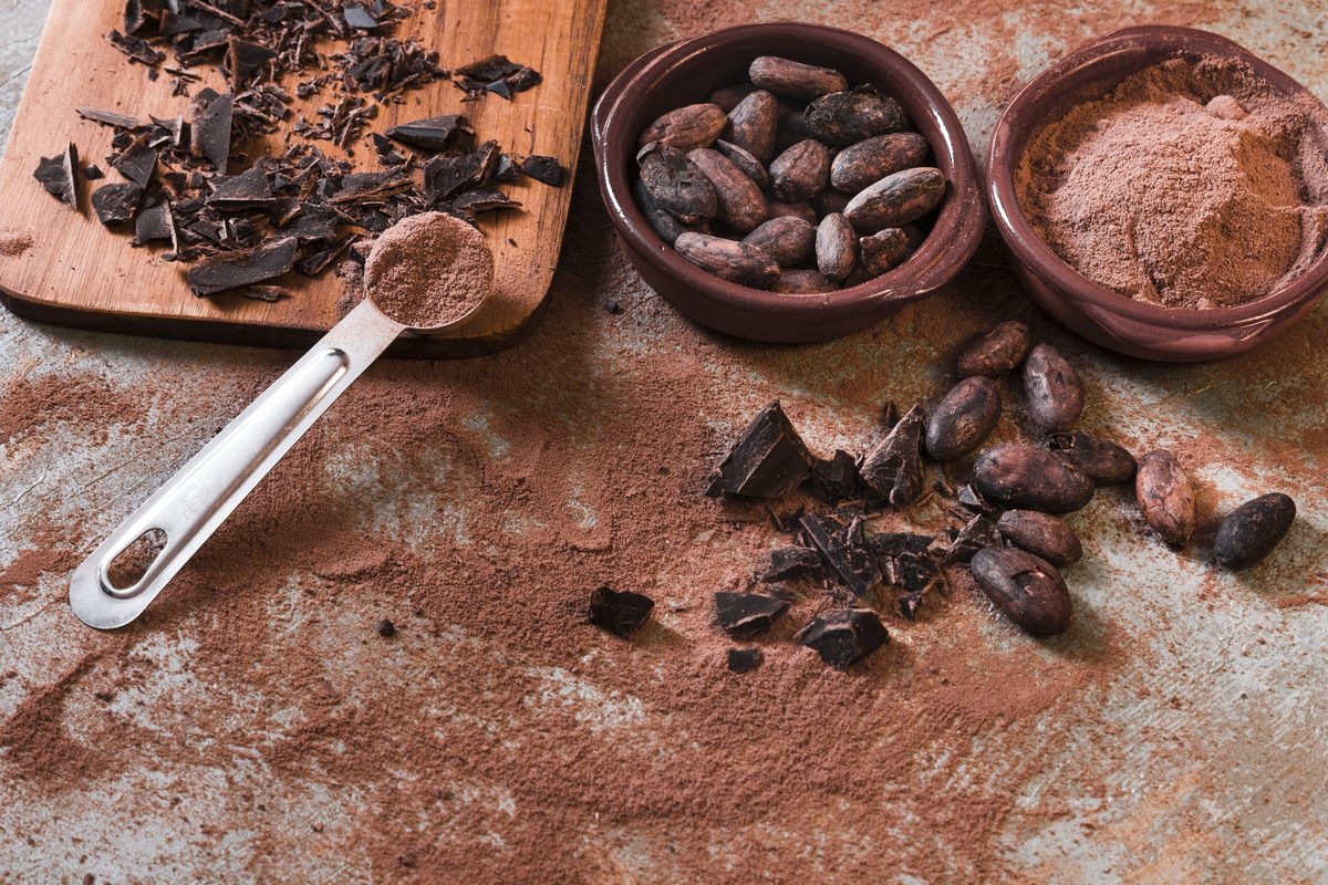 Dark chocolate shavings, beans and cocoa powder with a measuring spoon