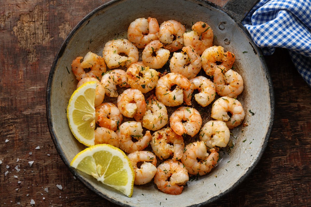 Peeled prawns thoroughly cooked in a frying pan with lemon