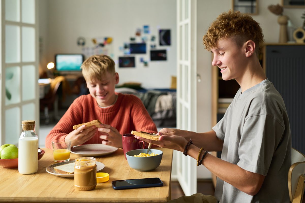 Two teenagers having breakfast at the kitchen table