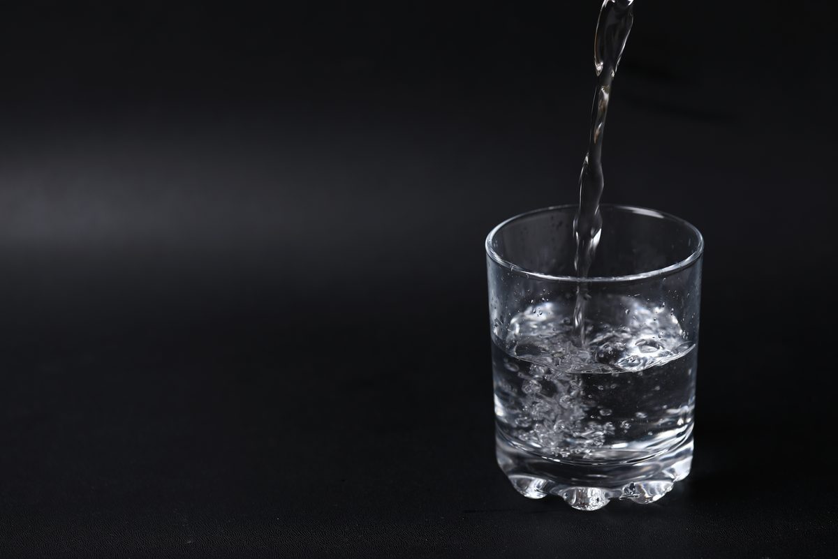 Water poured into a clear glass on a black background