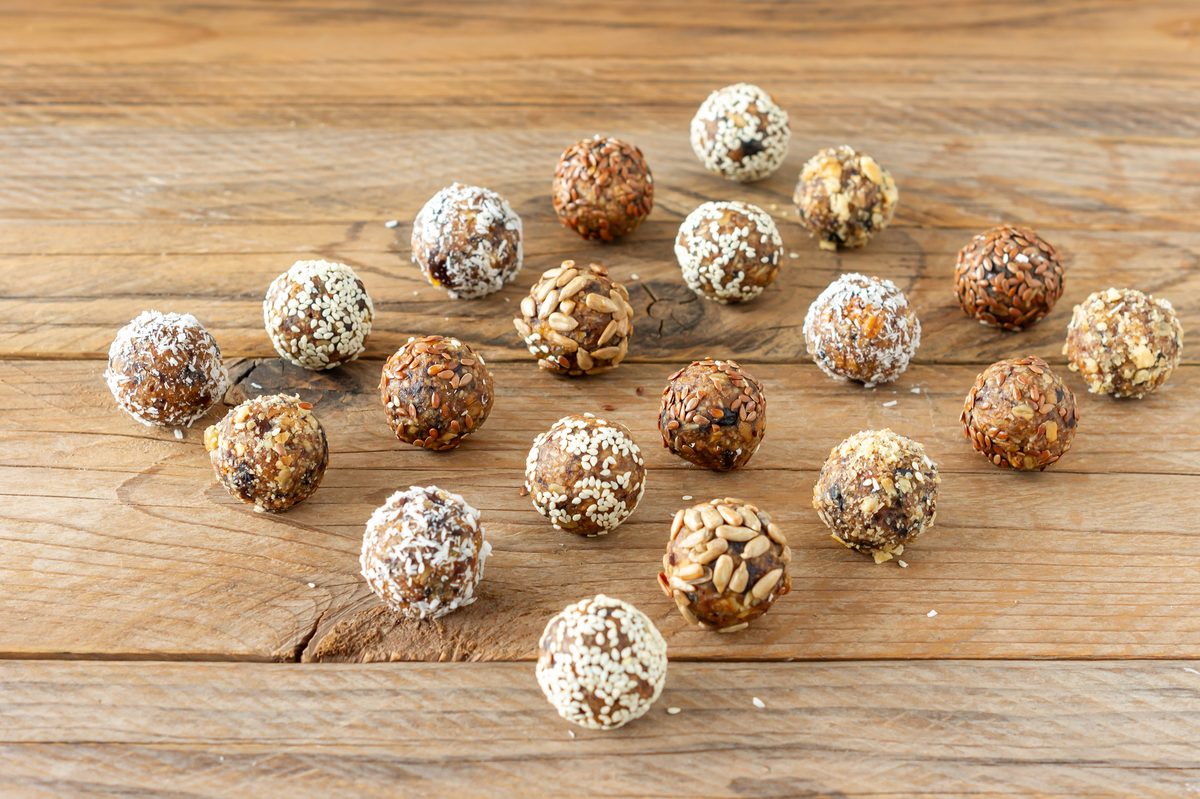 Date energy balls coated in seeds and coconut on a wooden table