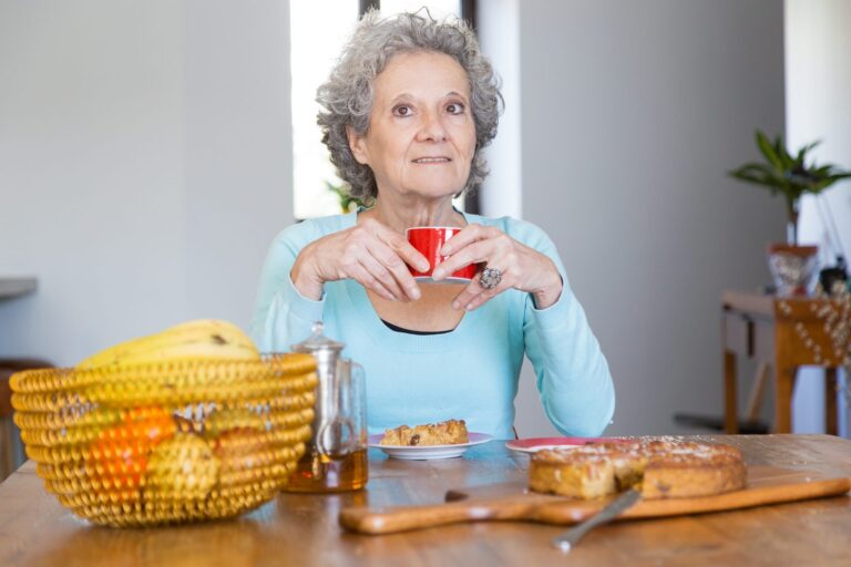 Elderly woman at a table with a cup and a slice of tart