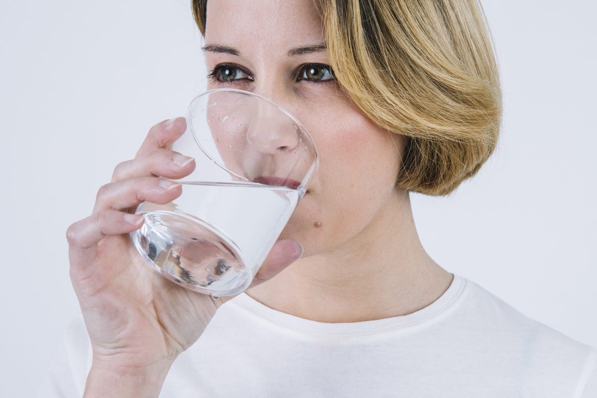 Femme blonde buvant un verre d'eau fraîche