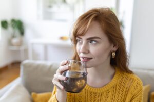 Femme buvant un verre d'eau dans son salon