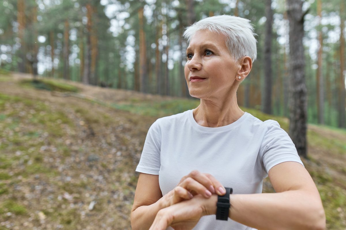 Woman checking her smartwatch during a cardio session in a forest