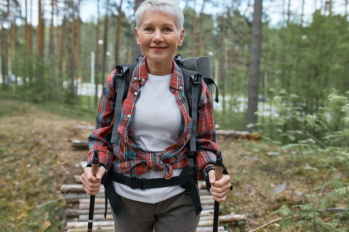 Woman in her fifties doing Nordic walking in a forest