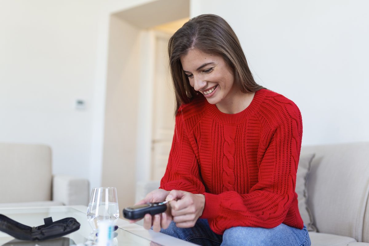 Woman measuring her blood glucose with a finger prick in her living room