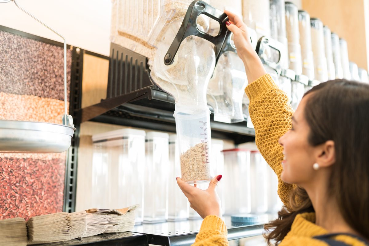 Woman filling a jar with loose cereals in a grocery shop
