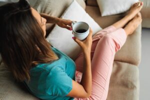 Femme se détendant sur un canapé avec une tasse de thé