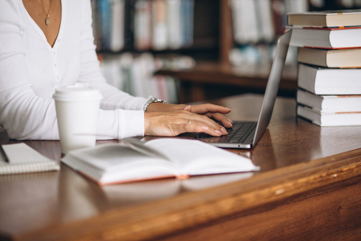 Femme travaillant sur un ordinateur portable entourée de livres