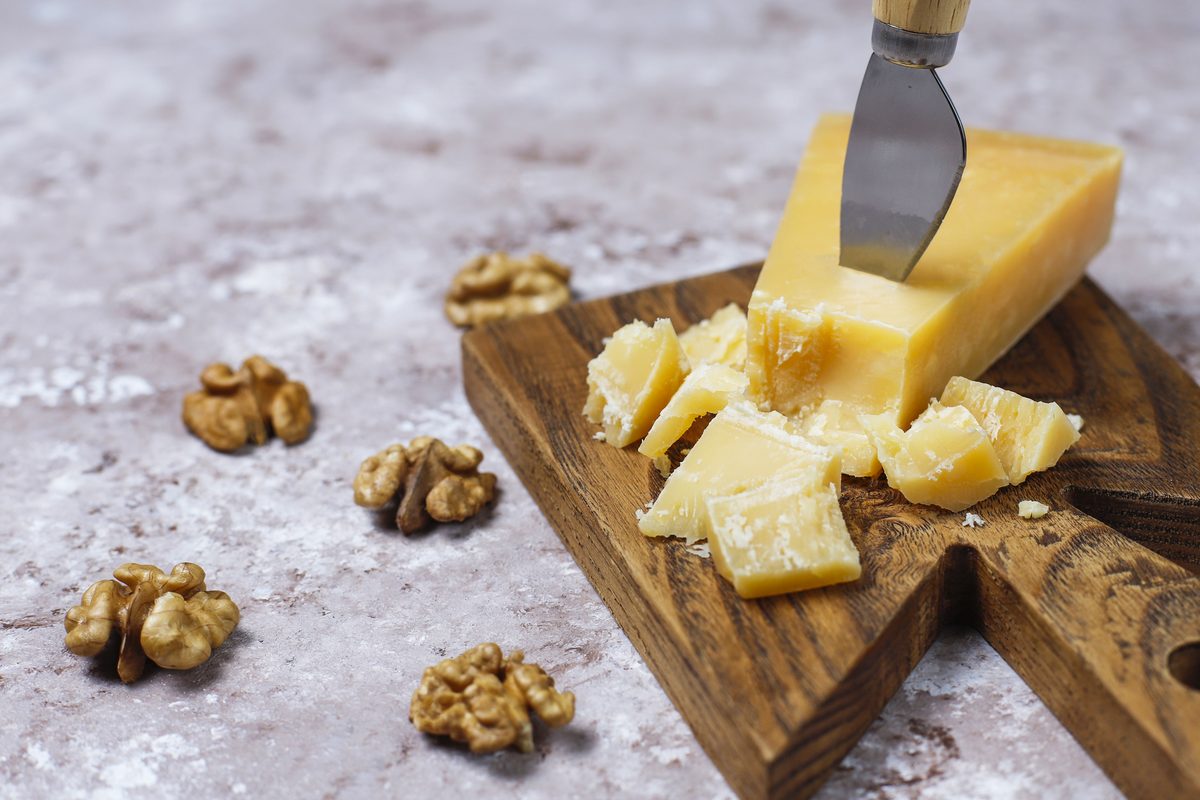 Hard cheese cut into cubes on a board with walnut halves