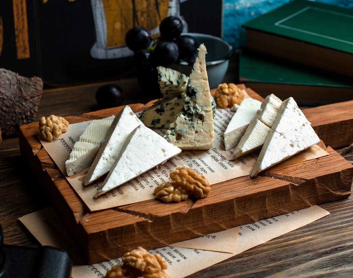 Blue cheese and white firm cheese on a board with walnuts