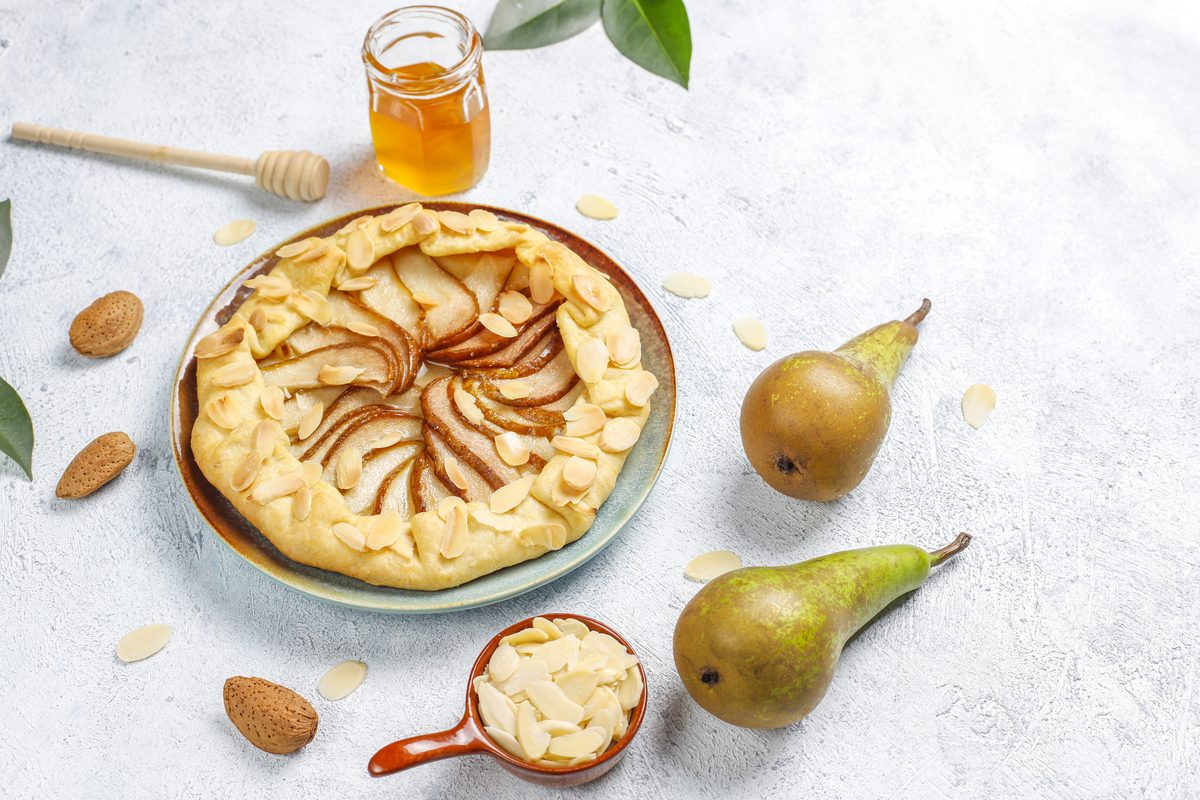 Rustic pear and almond tart next to fresh pears
