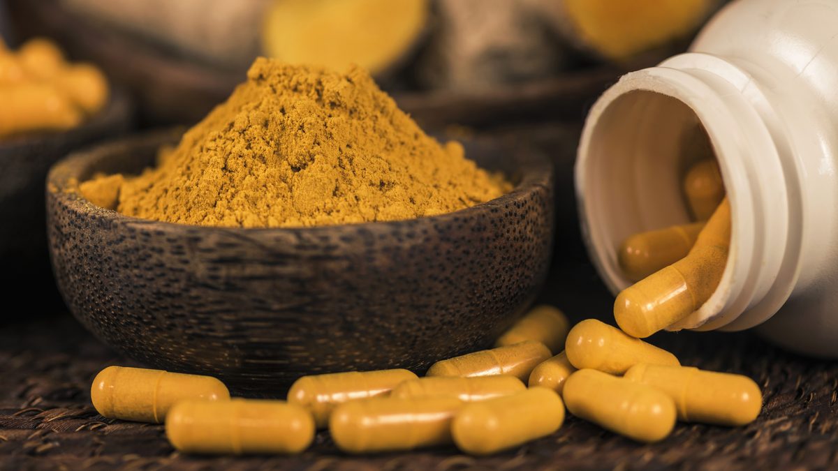 Curcumin capsules next to turmeric powder