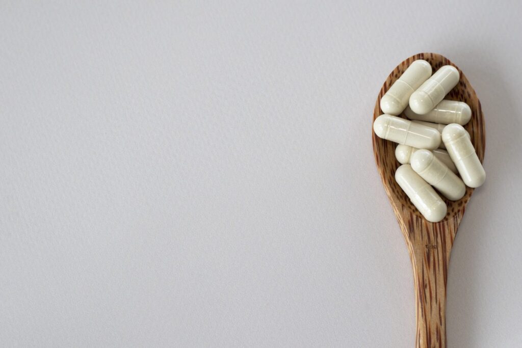 Beige probiotic capsules in a wooden spoon