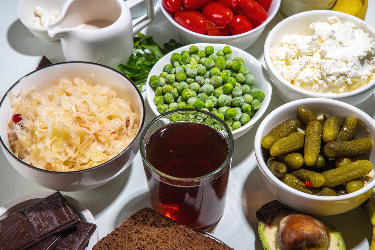 Probiotic capsules surrounded by fermented foods on a marble background