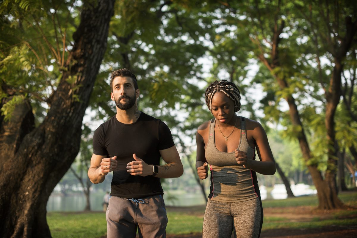 Homme et femme faisant un footing sous les arbres d'un parc