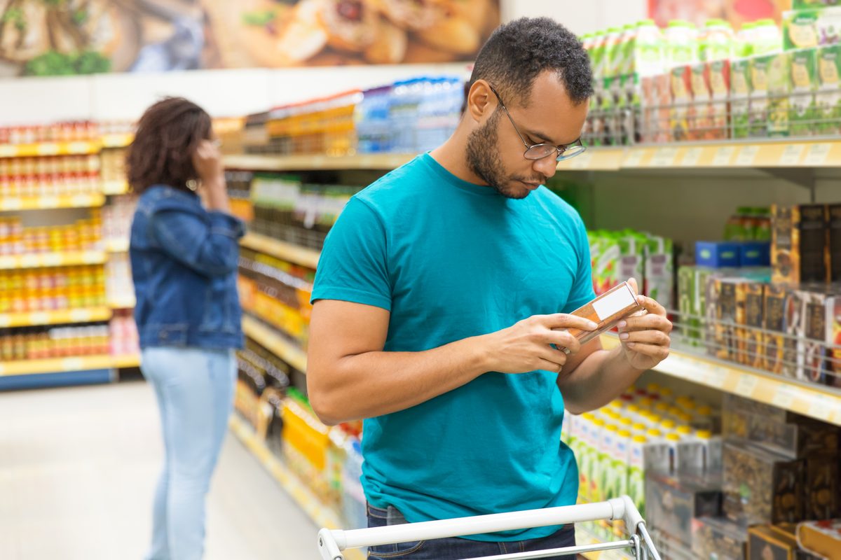 Man reading the nutrition information on a package in a supermarket