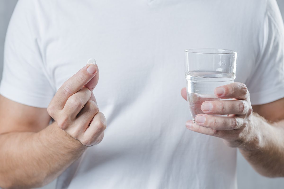 Man holding a white tablet and a glass of water