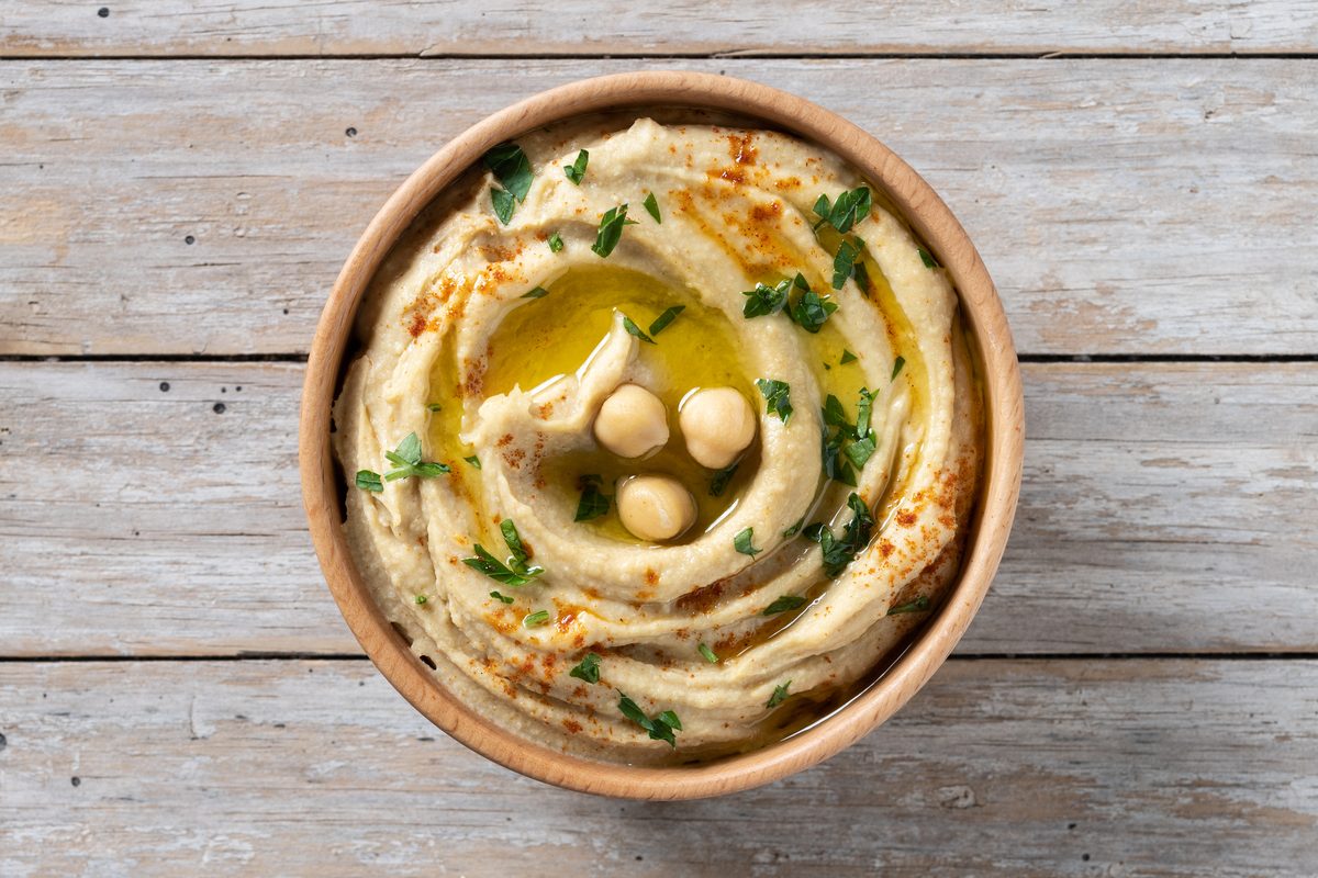 Homemade hummus in a wooden bowl, chickpeas, paprika and olive oil