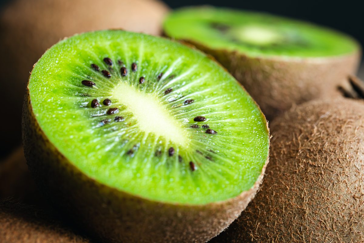 Close-up of a kiwi cut in half among whole kiwis