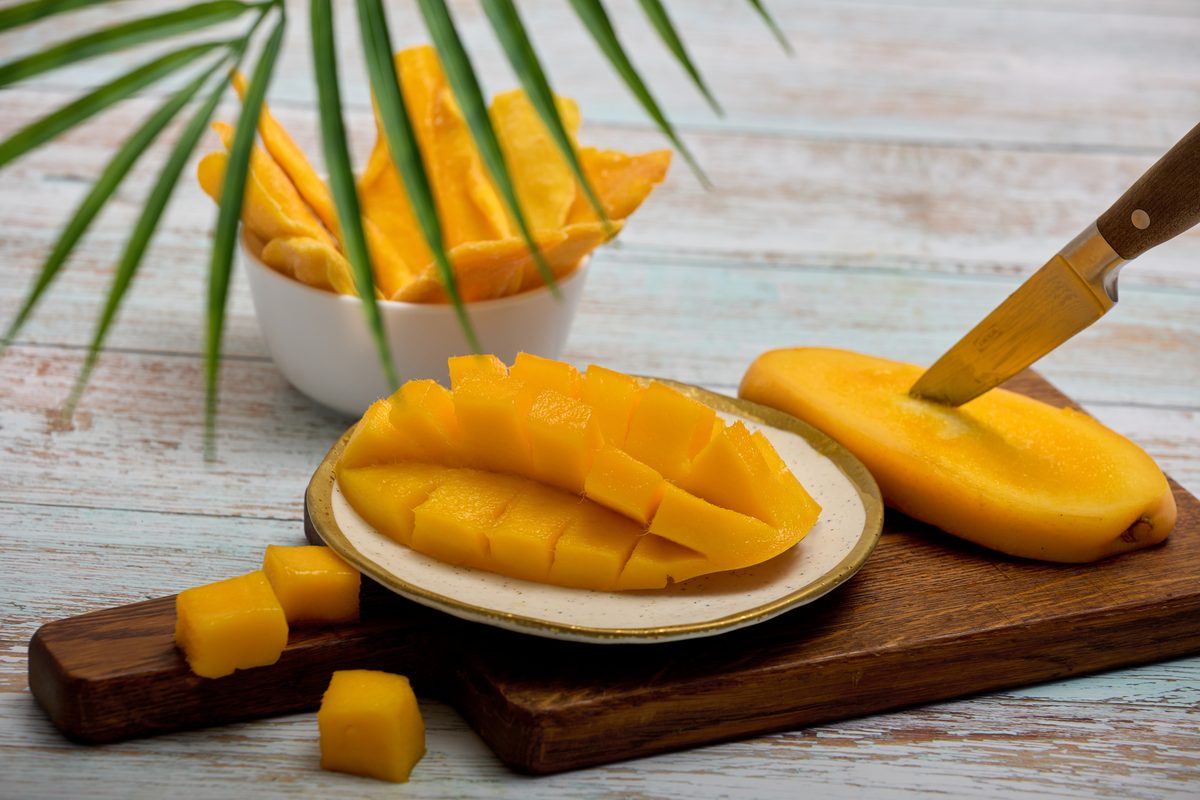 Fresh mango cut into a hedgehog pattern on a wooden board