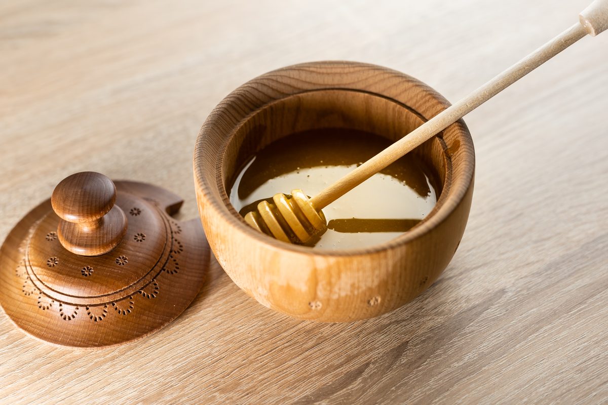 Honey in a wooden pot with its honey dipper