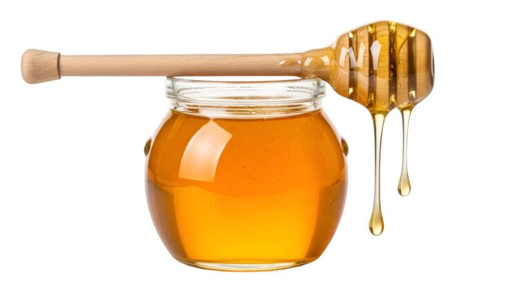 Golden honey dripping from a wooden spoon into a glass jar
