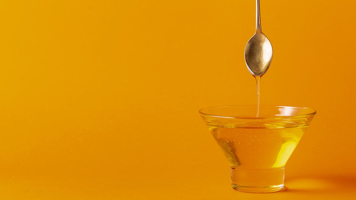 Miel qui s'écoule d'une cuillère dans un bol en verre