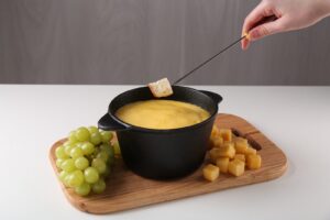 Morceau de pain trempé dans un caquelon de fondue au fromage