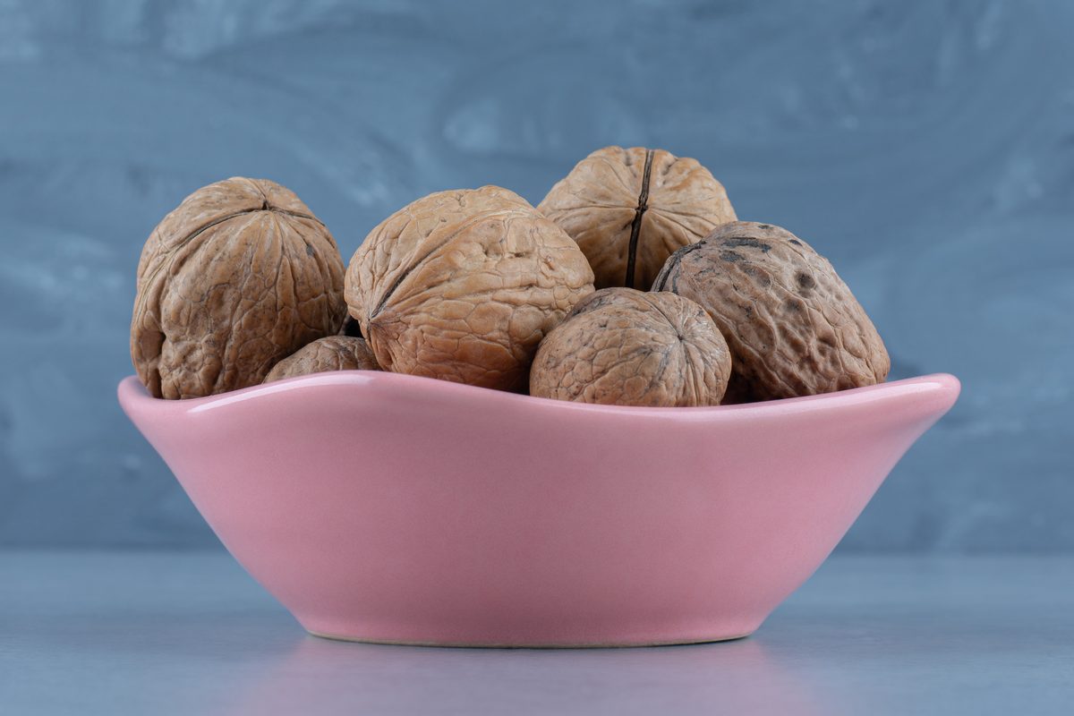 Noix entières dans leur coque, dans un bol rose